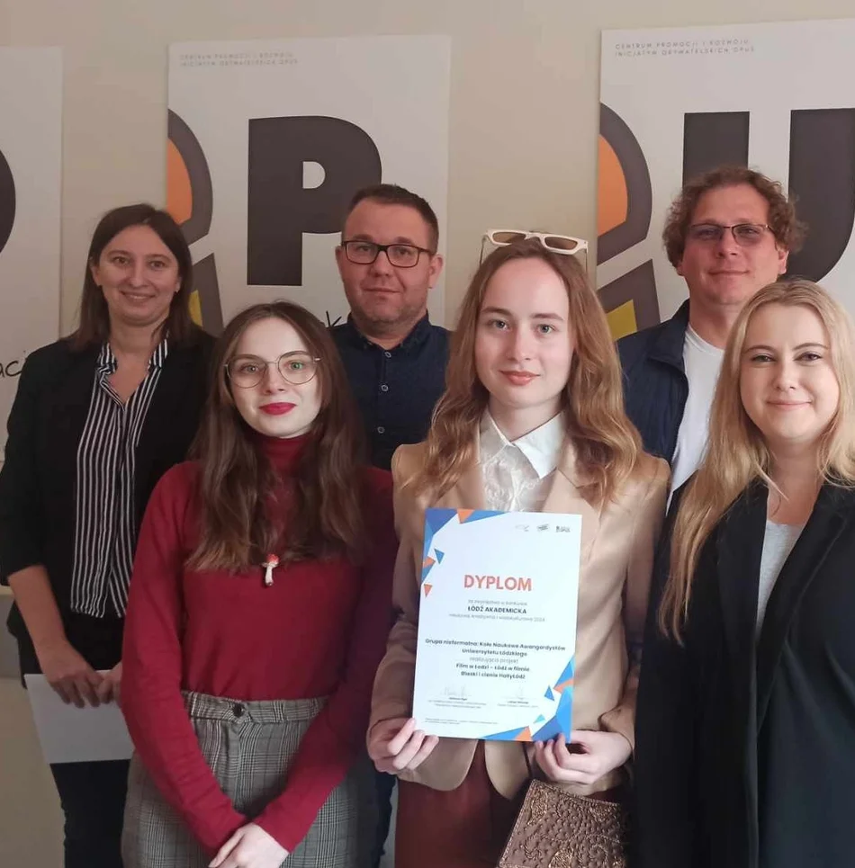 grupa studentów stoi z dyplomem